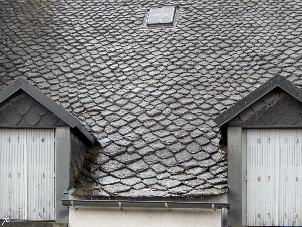 le toit de lauze vu du porche de l'église à Saint Sauves d'Auvergne